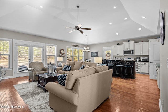 living area featuring light wood-type flooring, a raised ceiling, french doors, and recessed lighting