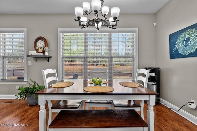 dining area featuring baseboards, visible vents, a chandelier, and wood finished floors