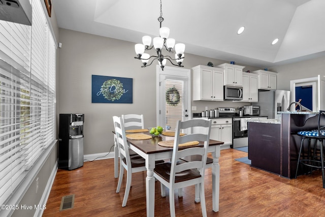 dining area with lofted ceiling, visible vents, baseboards, and wood finished floors