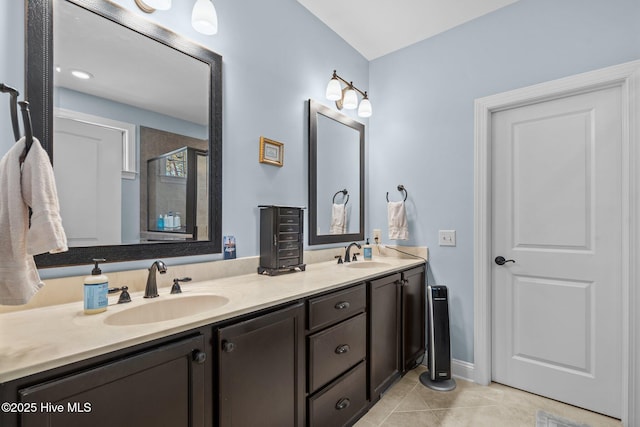 bathroom featuring a stall shower, tile patterned flooring, a sink, and double vanity