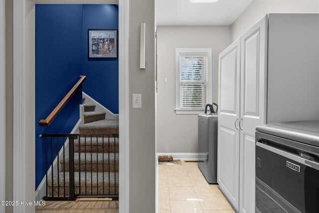 laundry area featuring light tile patterned floors, washing machine and clothes dryer, and baseboards