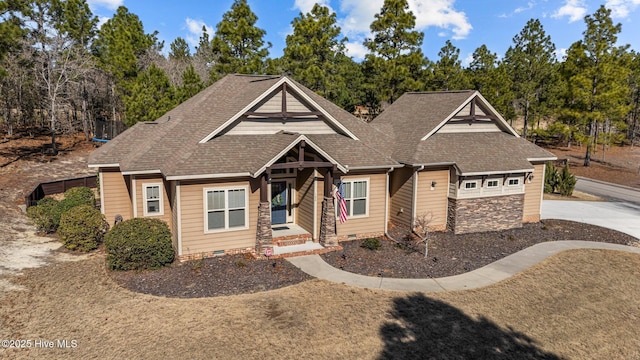 craftsman-style house with stone siding, crawl space, and roof with shingles