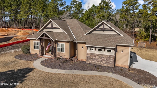 craftsman house featuring stone siding, a shingled roof, and crawl space