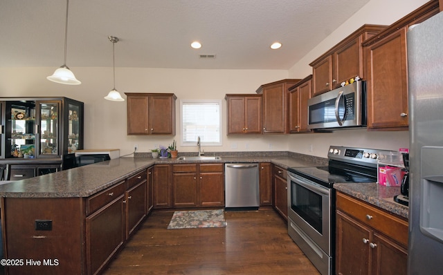 kitchen with sink, hanging light fixtures, dark hardwood / wood-style floors, kitchen peninsula, and stainless steel appliances