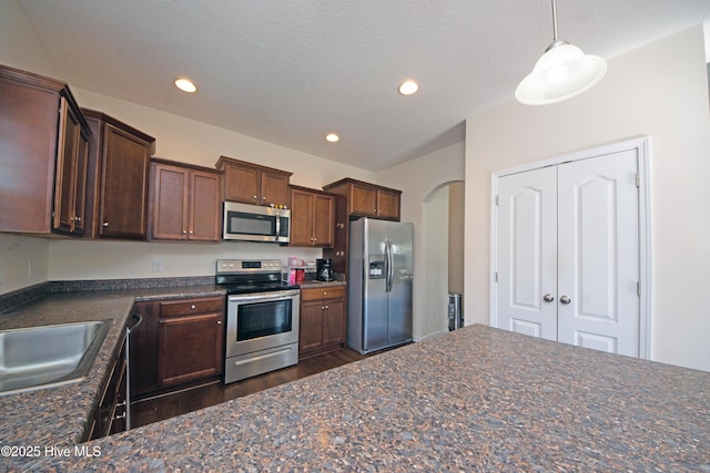 kitchen featuring stainless steel appliances, decorative light fixtures, sink, and a textured ceiling