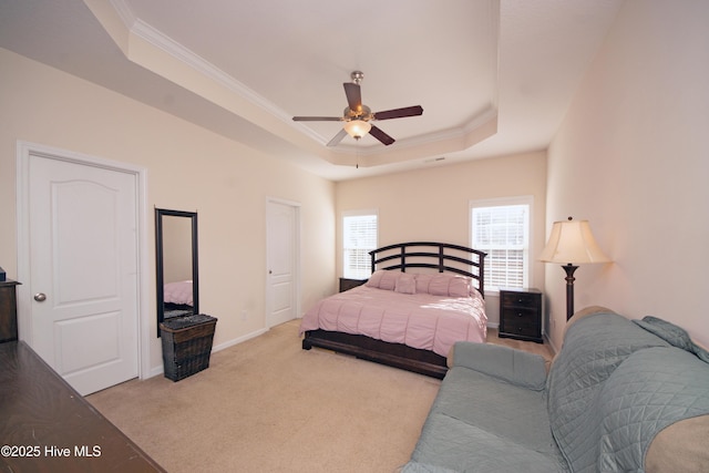 bedroom featuring ornamental molding, light carpet, ceiling fan, and a tray ceiling