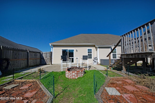 rear view of property with an outdoor fire pit, a yard, and a patio