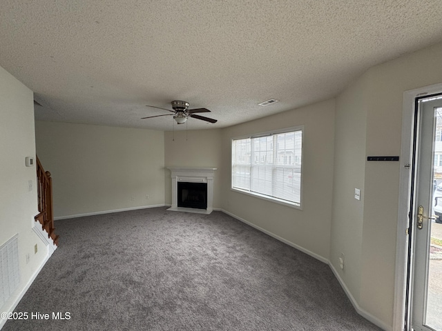 unfurnished living room featuring ceiling fan, a textured ceiling, a healthy amount of sunlight, and carpet flooring