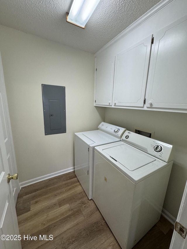 washroom with hardwood / wood-style floors, electric panel, cabinets, a textured ceiling, and separate washer and dryer