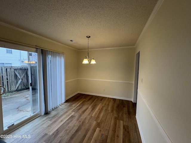 unfurnished dining area with wood-type flooring, ornamental molding, a textured ceiling, and a chandelier