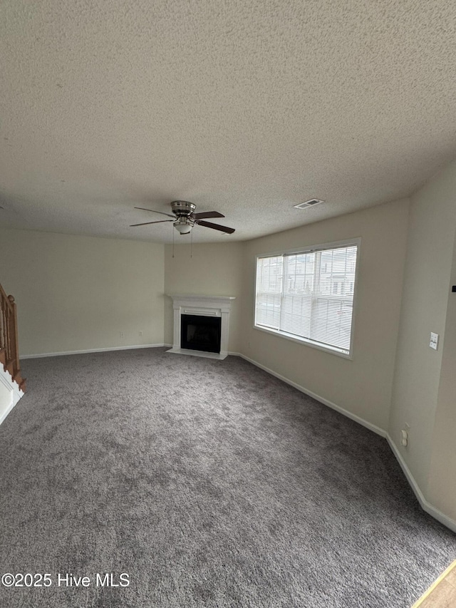 unfurnished living room featuring a textured ceiling, ceiling fan, and carpet