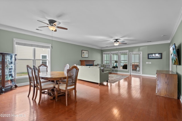 dining area with crown molding, a fireplace, visible vents, and hardwood / wood-style floors