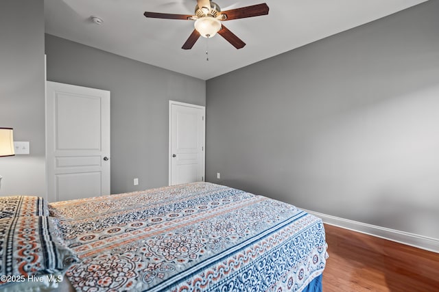 bedroom featuring a ceiling fan, baseboards, and wood finished floors