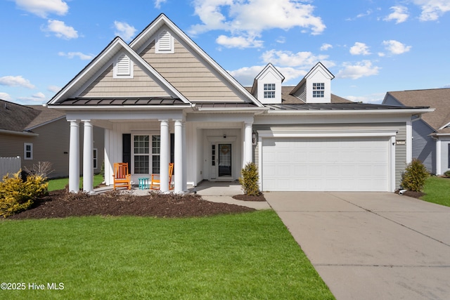 view of front of house featuring a garage, driveway, a standing seam roof, a front lawn, and a porch