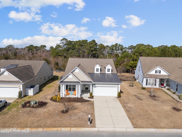 view of front facade featuring covered porch, a standing seam roof, metal roof, a garage, and driveway