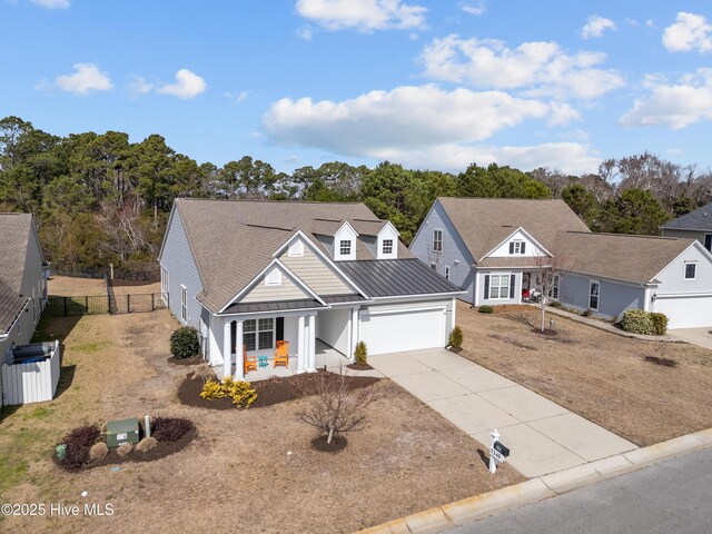 view of front of property featuring a porch, concrete driveway, a standing seam roof, metal roof, and fence