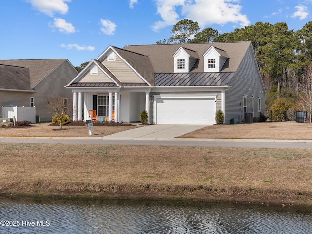 view of front facade with cooling unit, a water view, fence, driveway, and a standing seam roof