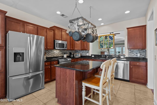 kitchen featuring stainless steel appliances, a center island, visible vents, and light tile patterned floors