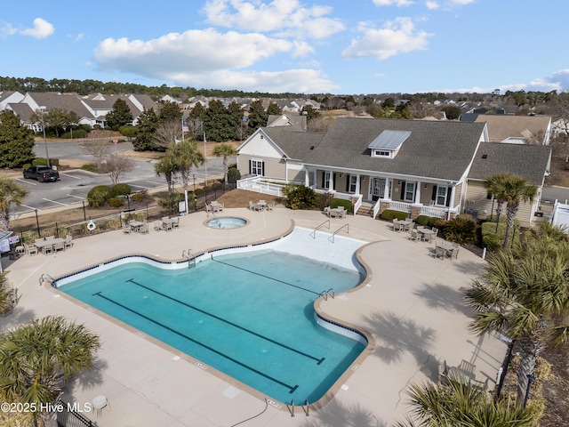 community pool featuring a community hot tub, a patio area, fence, and a residential view