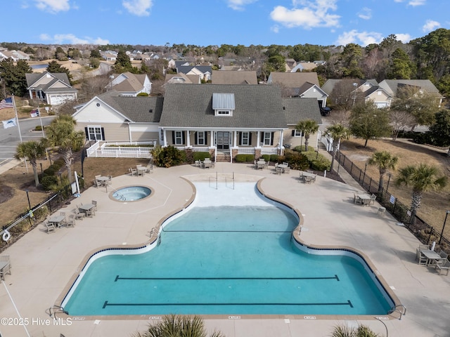 community pool featuring a patio area, a residential view, fence, and a community hot tub