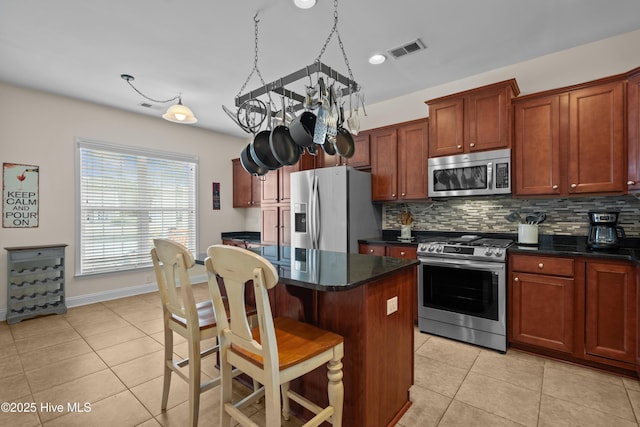 kitchen with stainless steel appliances, visible vents, a kitchen island, and light tile patterned floors