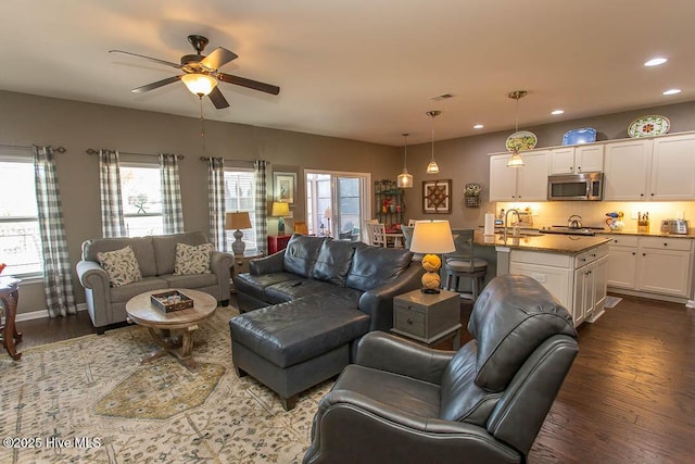 living room featuring dark wood-type flooring, ceiling fan, and sink