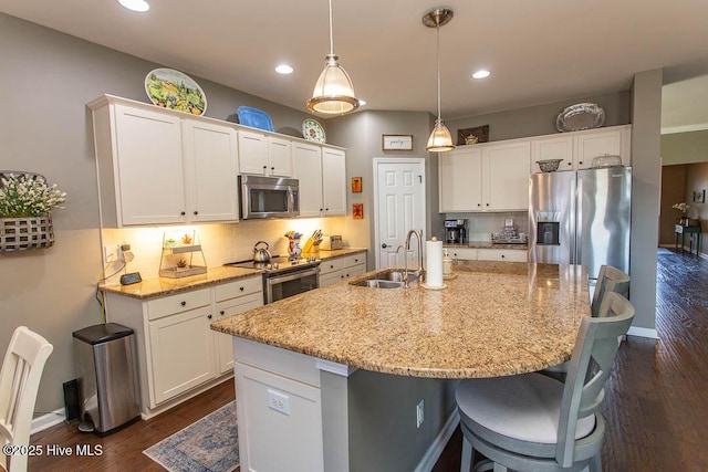 kitchen featuring sink, white cabinetry, a kitchen island with sink, stainless steel appliances, and light stone countertops