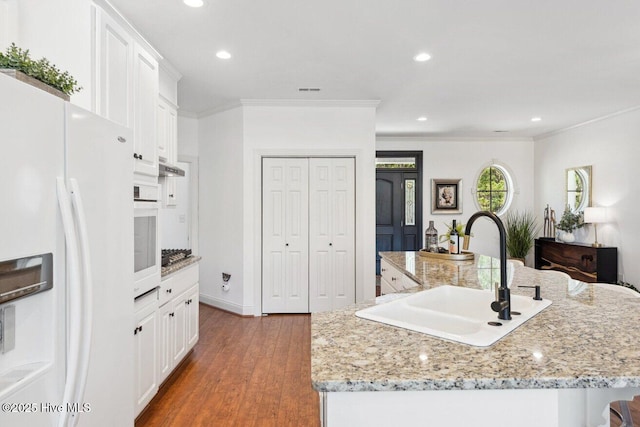 kitchen with a large island, white appliances, crown molding, and a sink