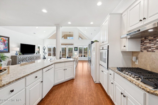 kitchen featuring white appliances, lofted ceiling, a sink, french doors, and open floor plan