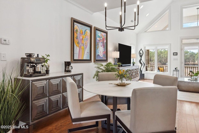 dining space with a notable chandelier, dark wood finished floors, high vaulted ceiling, and crown molding