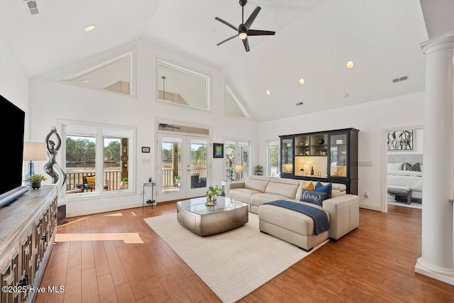 living room with visible vents, high vaulted ceiling, wood-type flooring, ceiling fan, and ornate columns