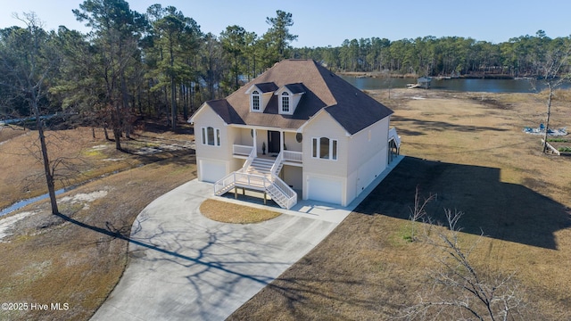 view of front of home featuring a water view, covered porch, concrete driveway, an attached garage, and stairs