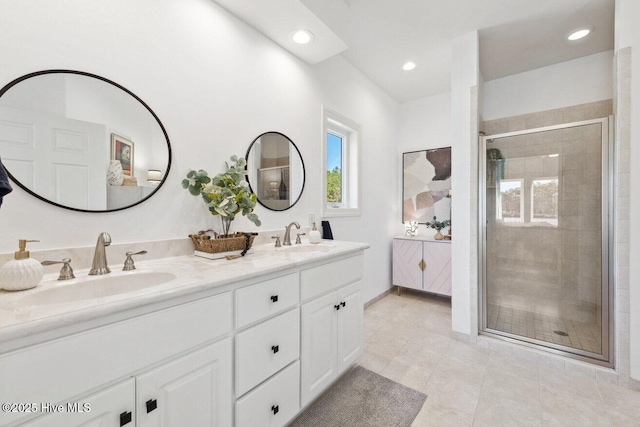 full bathroom featuring double vanity, a shower stall, and a sink