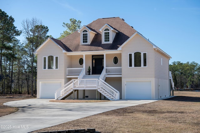 coastal inspired home with stairs, a porch, concrete driveway, and an attached garage