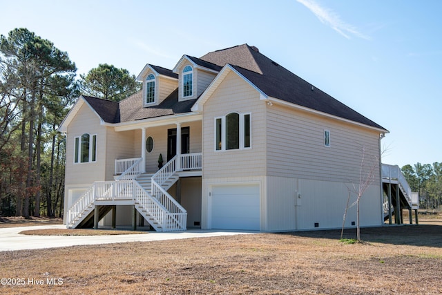 beach home with stairway, a porch, a shingled roof, and a garage