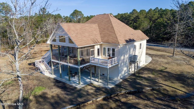 rear view of property featuring a wooden deck, stairs, cooling unit, driveway, and a patio