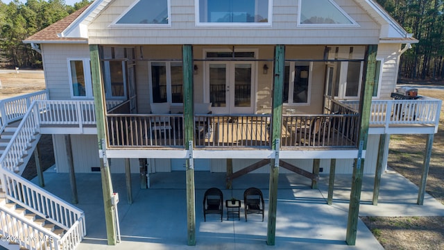 rear view of house featuring stairway, concrete driveway, a shingled roof, a carport, and a patio area