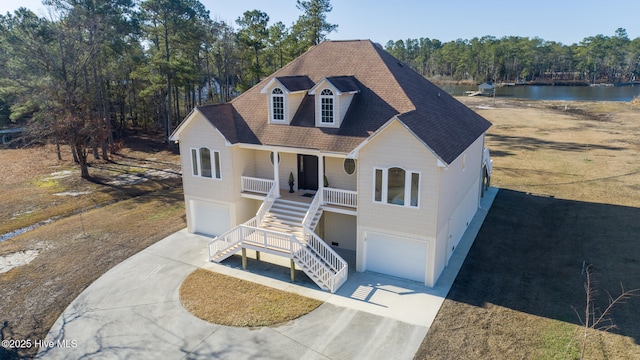 view of front of property with roof with shingles, covered porch, stairs, concrete driveway, and a garage