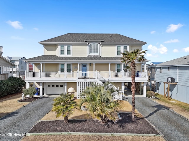 coastal inspired home with a porch, a shingled roof, stairway, a carport, and gravel driveway