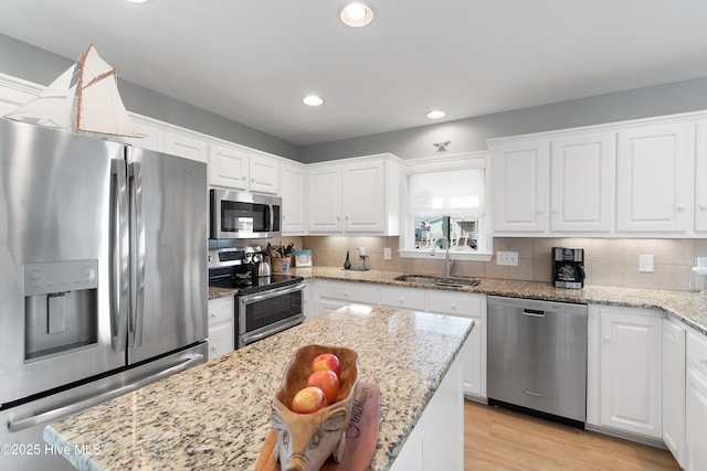 kitchen featuring recessed lighting, a sink, white cabinets, appliances with stainless steel finishes, and light wood finished floors