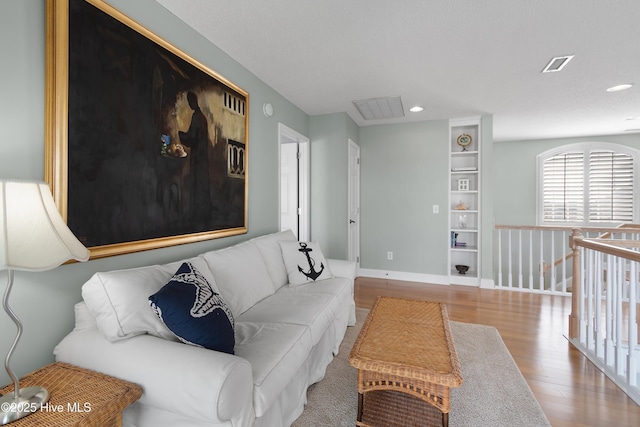 living area featuring baseboards, visible vents, wood finished floors, and recessed lighting