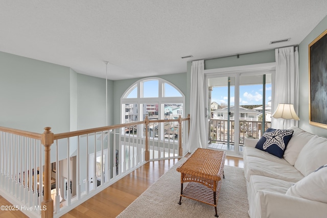 living room with a textured ceiling, wood finished floors, and visible vents