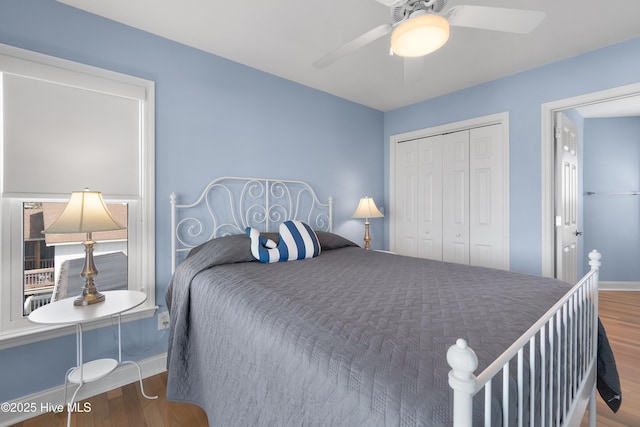 bedroom featuring a ceiling fan, a closet, baseboards, and wood finished floors