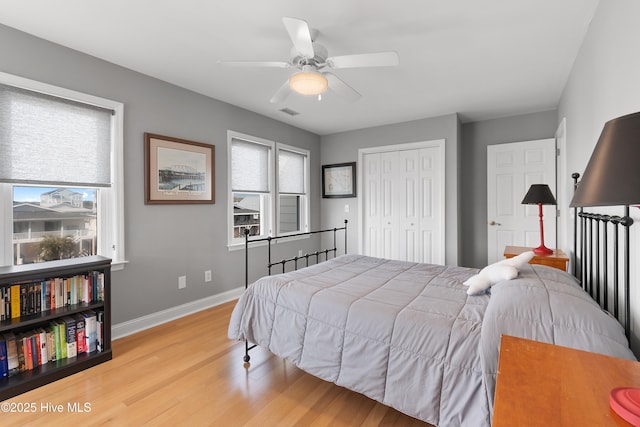 bedroom featuring a closet, baseboards, multiple windows, and light wood finished floors