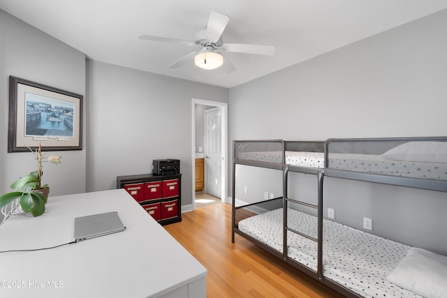 bedroom featuring light wood finished floors, ensuite bath, and a ceiling fan