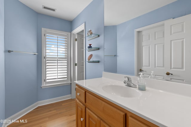 bathroom with visible vents, vanity, baseboards, and wood finished floors