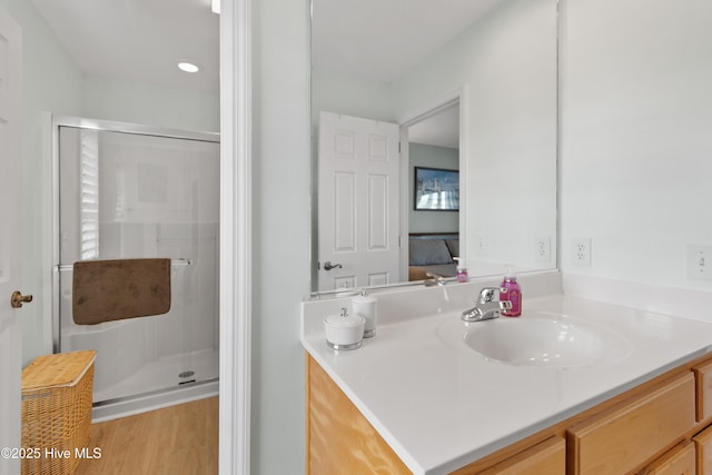 ensuite bathroom with a shower stall, wood finished floors, connected bathroom, and vanity