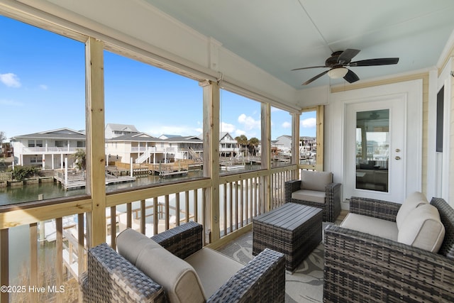 sunroom featuring a water view, a residential view, and a ceiling fan