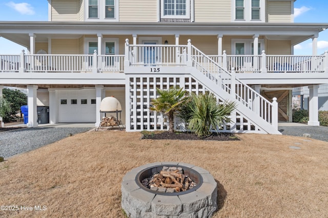 coastal inspired home with covered porch, gravel driveway, and stairs