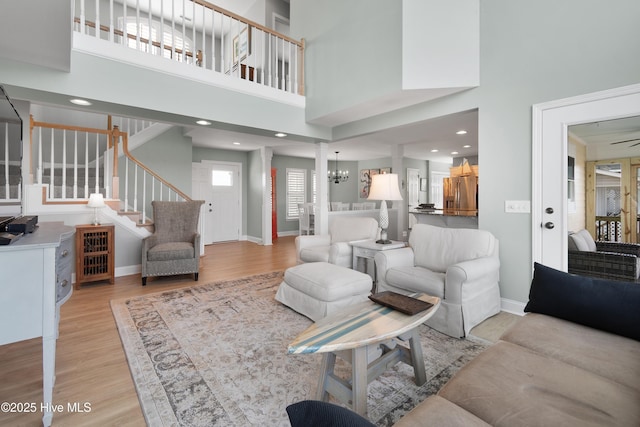 living area featuring light wood finished floors, stairway, and baseboards